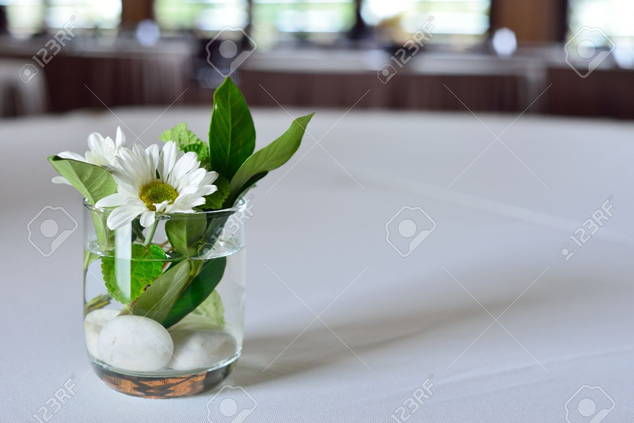 Deux Fleurs Blanches Feuilles Vertes Et Des Roches Blanches Sont Dcores Dans Un Vase De Verre Mettez Sur Le Dessus De Table De Restaurant with regard to measurements 1300 X 867